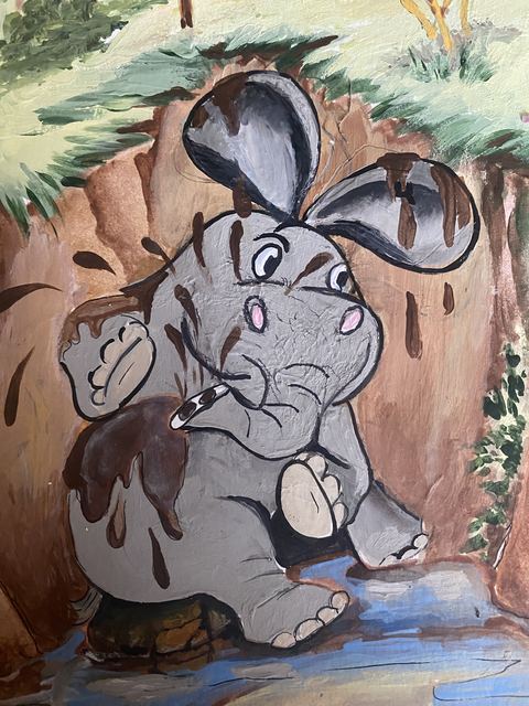 A gray elephant splashing happily down a muddy slide